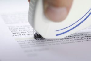 doigts tenant un rouleau correcteur blanc contre une feuille pour corriger un document