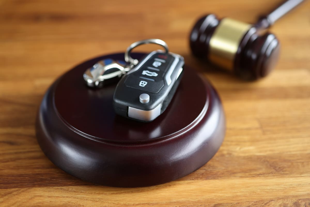 clé d'une auto posée sur un socle en bois près du marteau du juge ou gavel 
