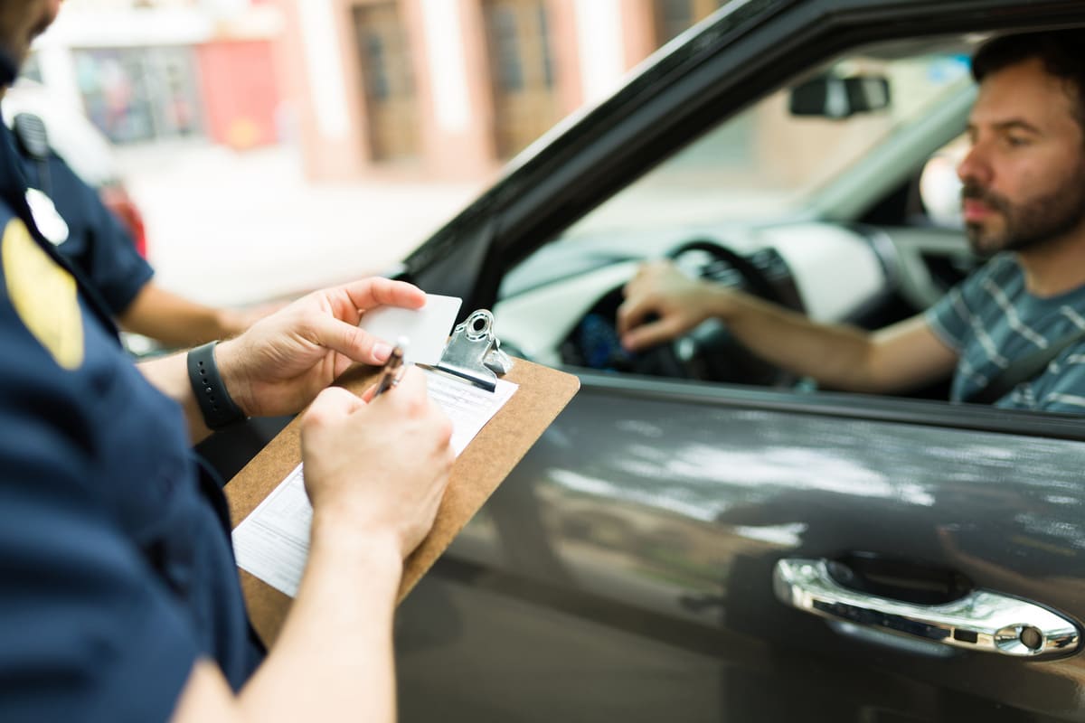 agent de police donnant une amende à un conducteur qui se trouve au volant de sa voiture 