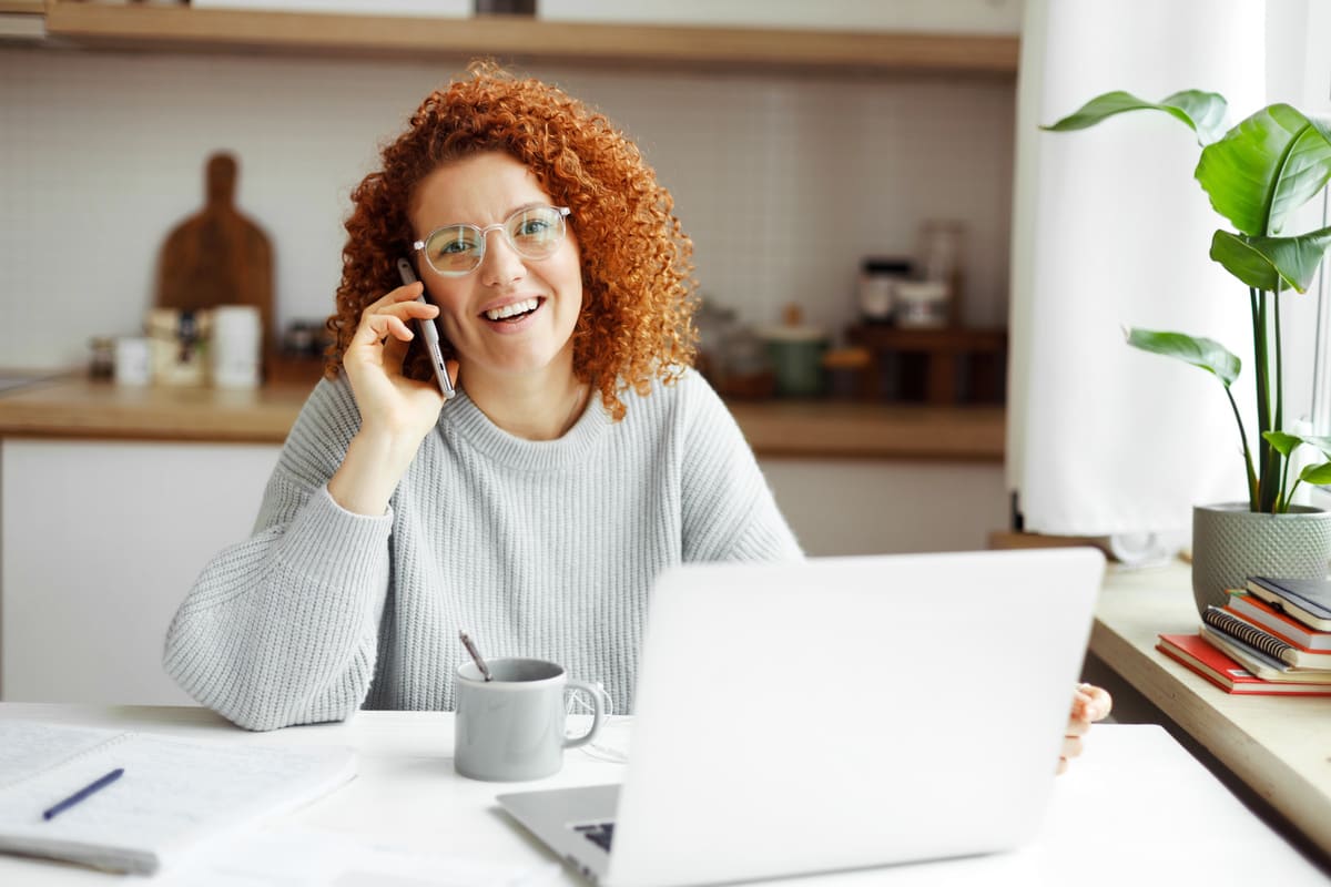 femme assis dans un bureau devant un ordinateur et en train d'appeler au téléphone 