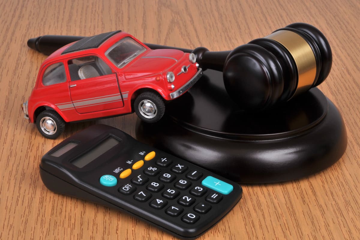 voiture rouge miniature près d'un marteau du juge et d'une calculatrice 